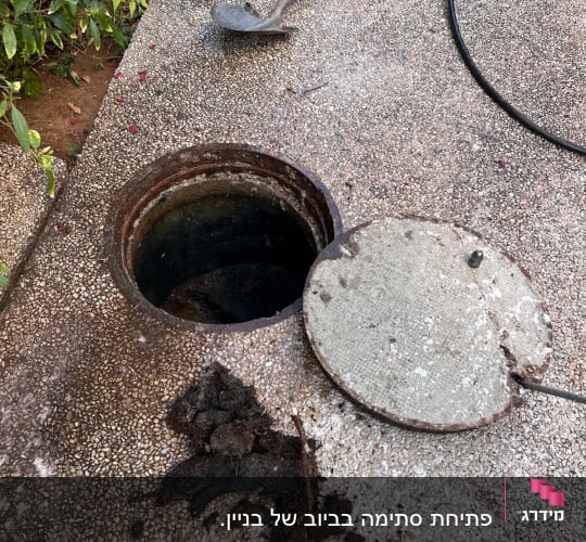 פתח ביוב פתוח עם מכסה בצד, צינור ושאריות לכלוך